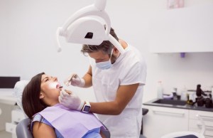 Dentist placing bridge over prepared teeth — seamless replacement for missing teeth