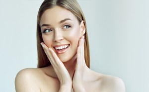 Woman gently touching smooth, glowing face — natural beauty and healthy skin